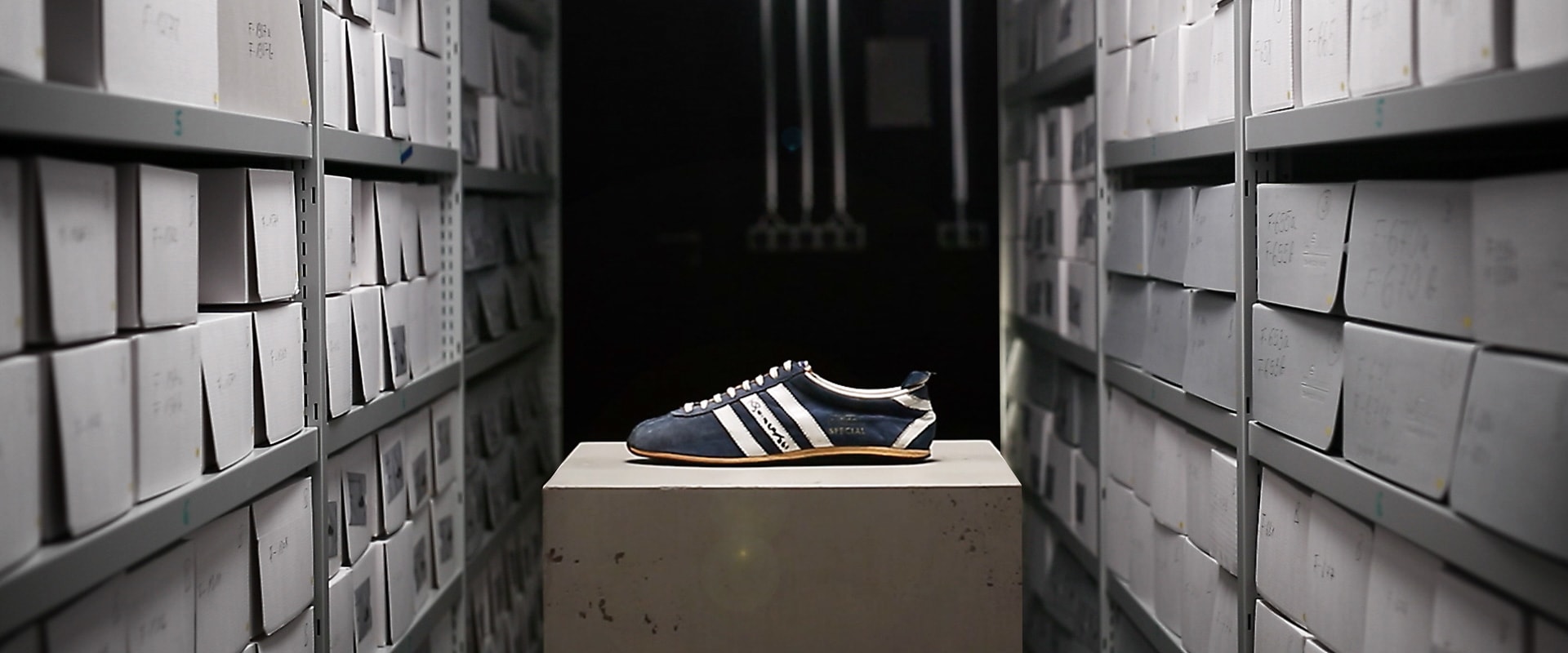 An Adidas shoe on a box in a storage room.