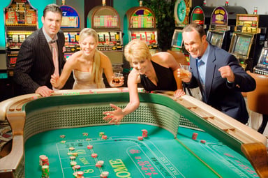 Happy gamblers rolling dice at a craps table
