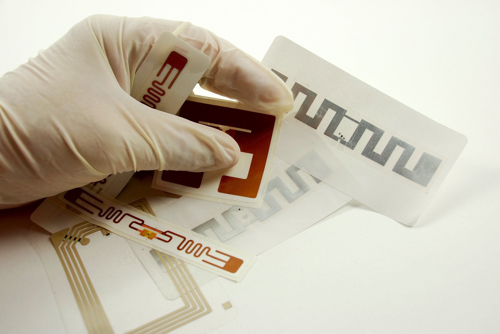 A hand, wearing a medical glove, holds several RFID tags.