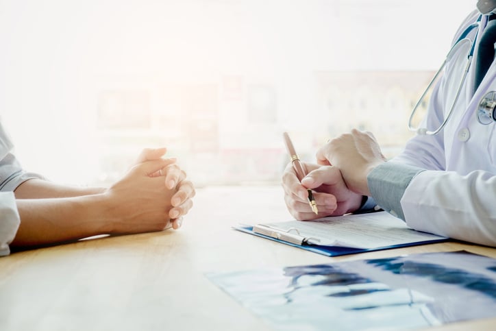 An individual sitting at a table with a doctor.