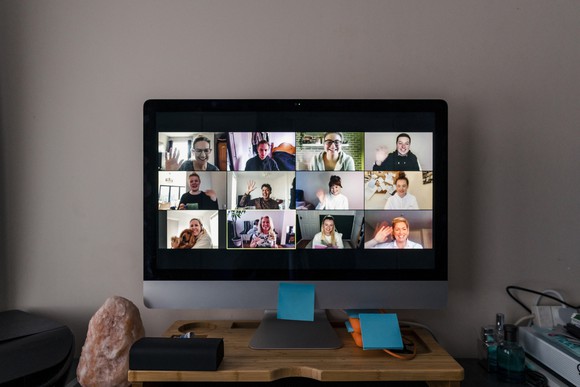 A video conference taking place on a computer with multiple people on the screen. 