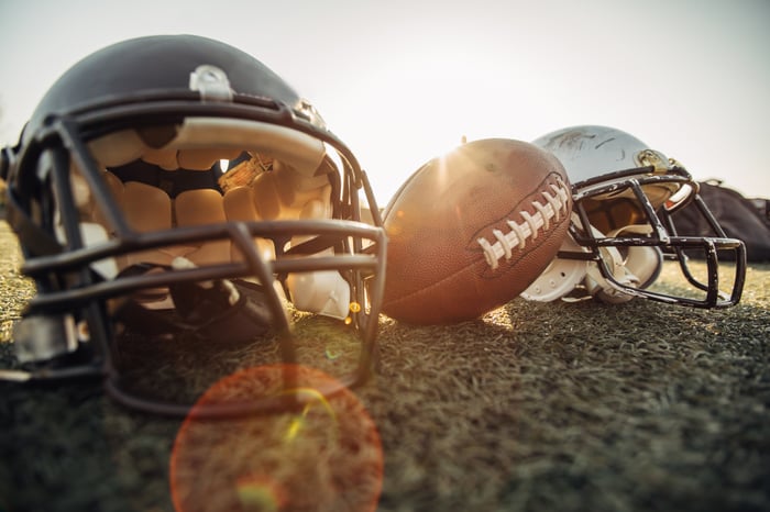 Football helmets and a football placed on a field. 