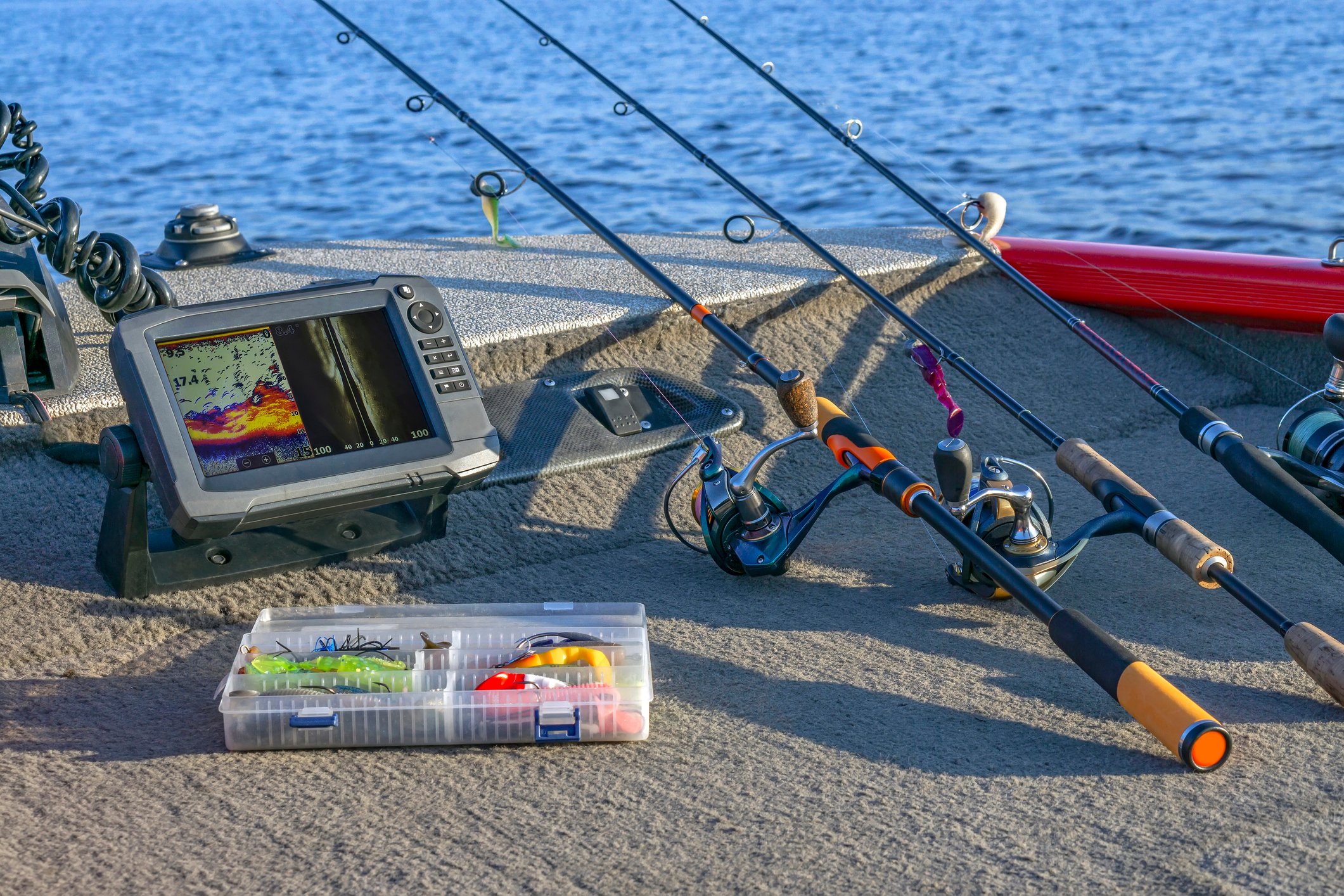 Fishing rods, lures, and a fishfinder on the deck of a boat