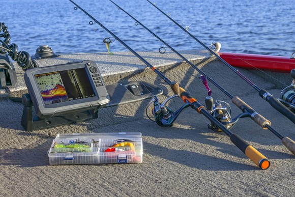 Fishing rods, lures, and a fishfinder on the deck of a boat