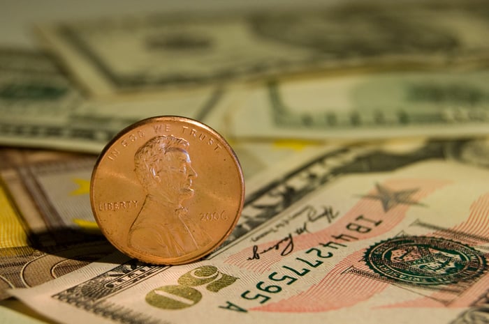 A penny standing on its edge atop a fifty-dollar bill