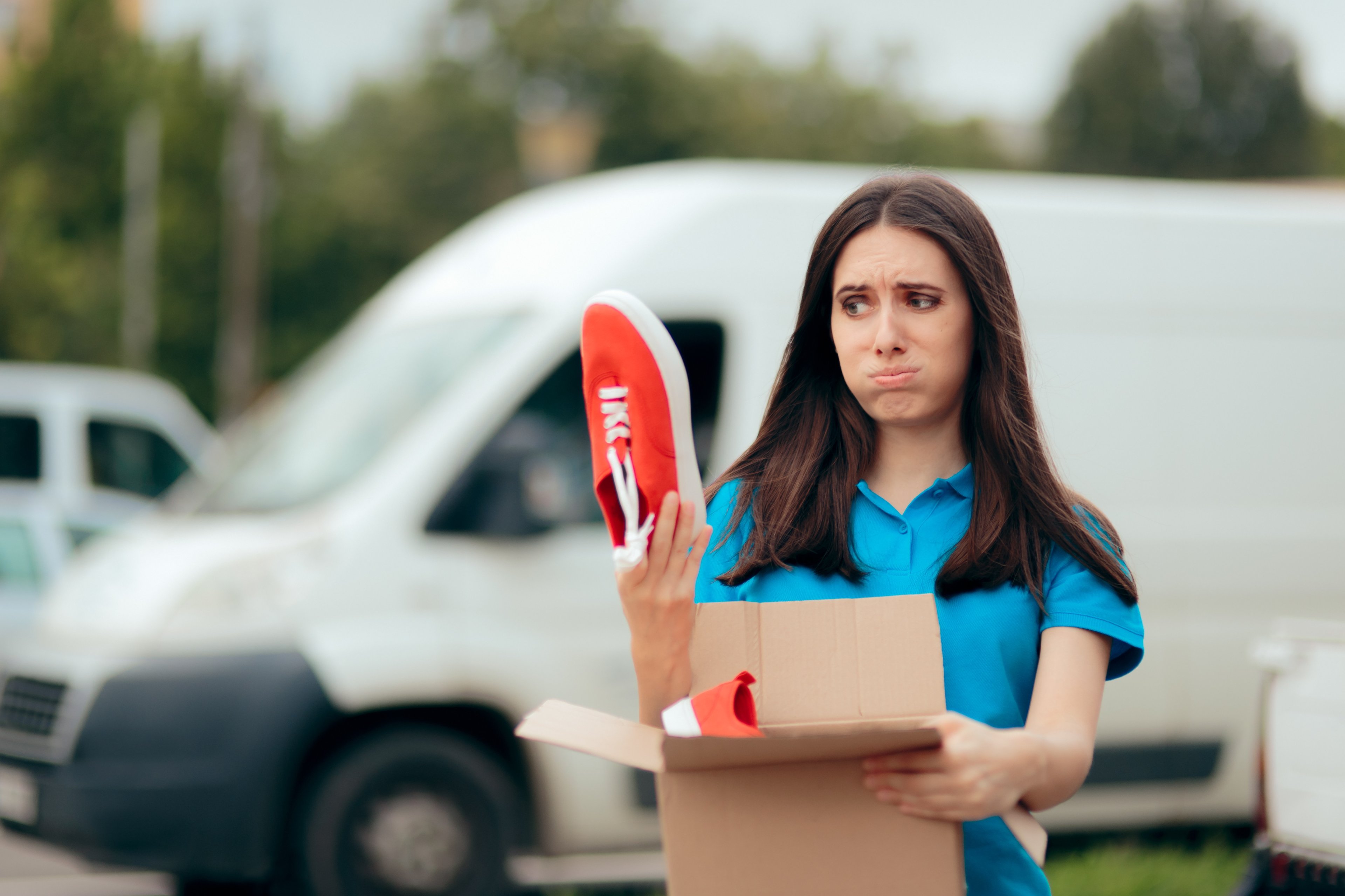 Women holding a sneaker after opening the package and looking disappointed. 