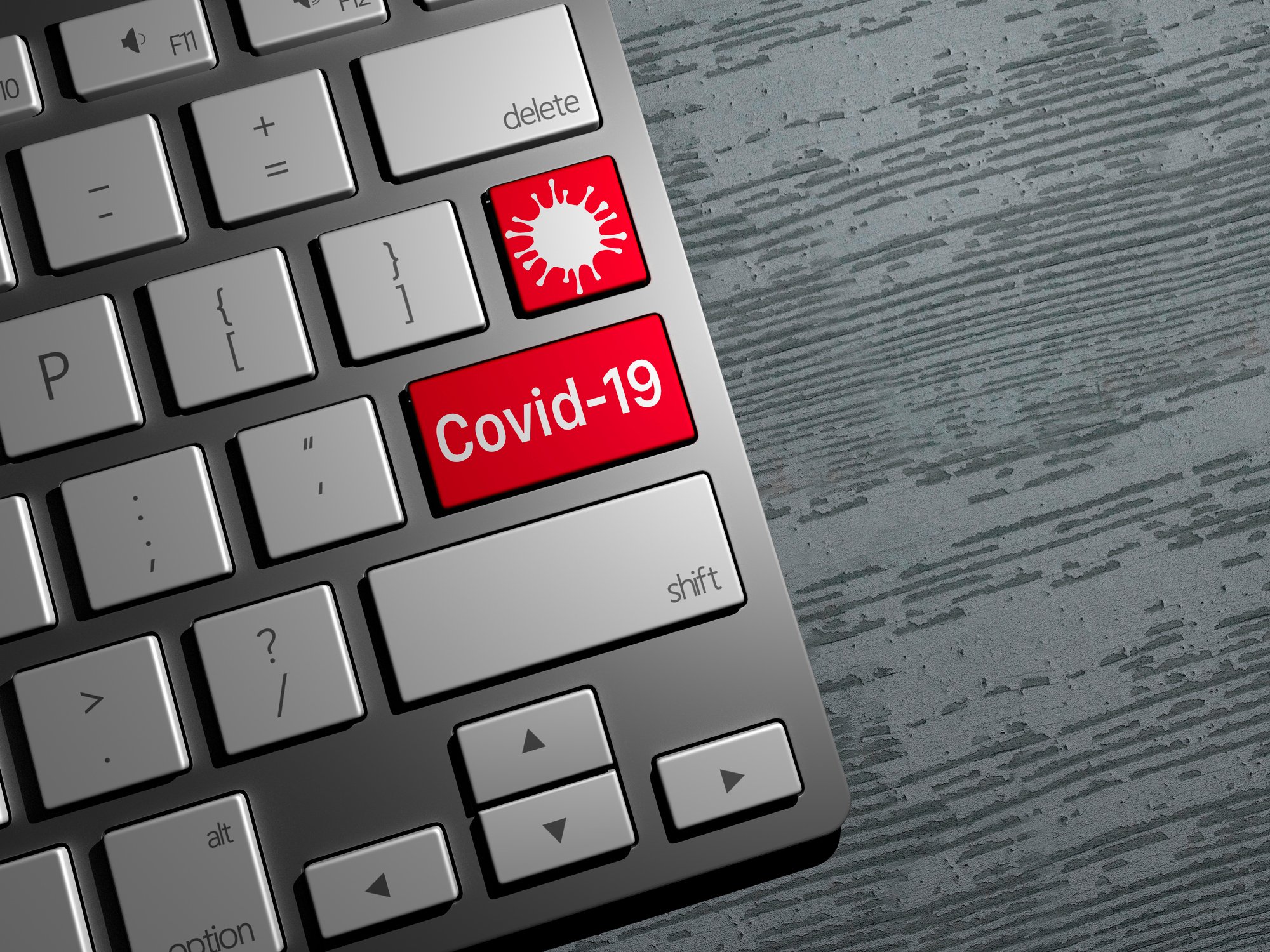 A computer keyboard sits on a desk with keys that are changed to show COVID-19 wording and a virus logo
