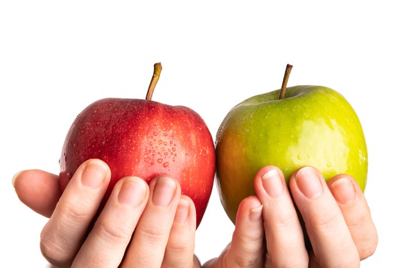 Two hands hold up a contrasting green apple and a red apple