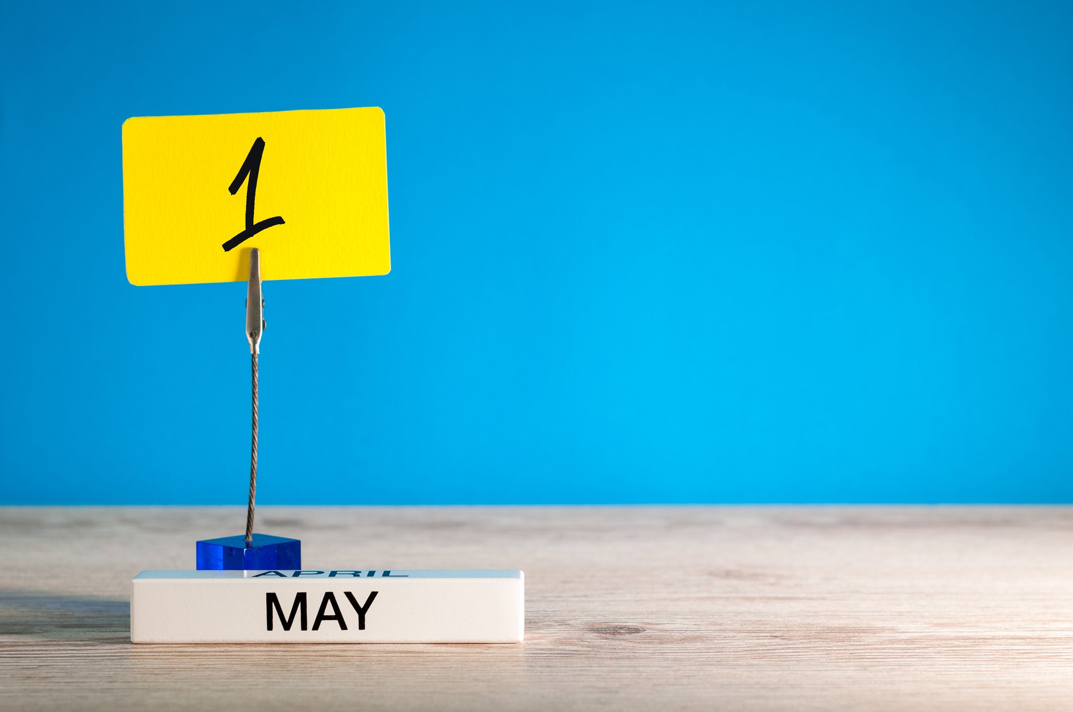 May printed on wood block in front of a yellow placard with the number 1 written on it