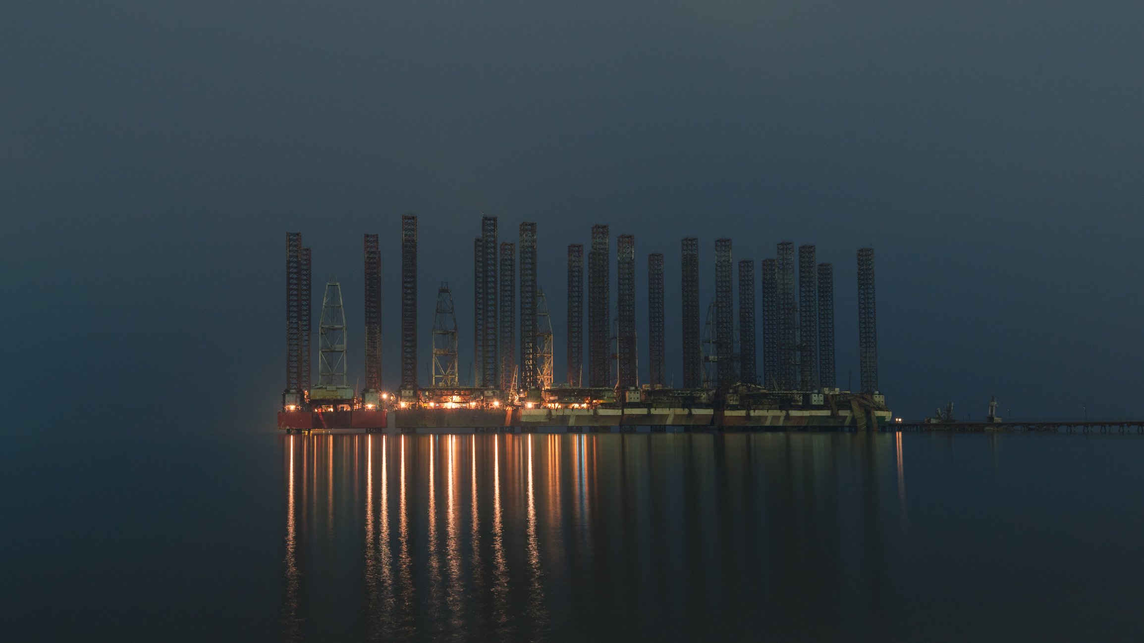 Several offshore drilling rigs sitting idle in darkness.