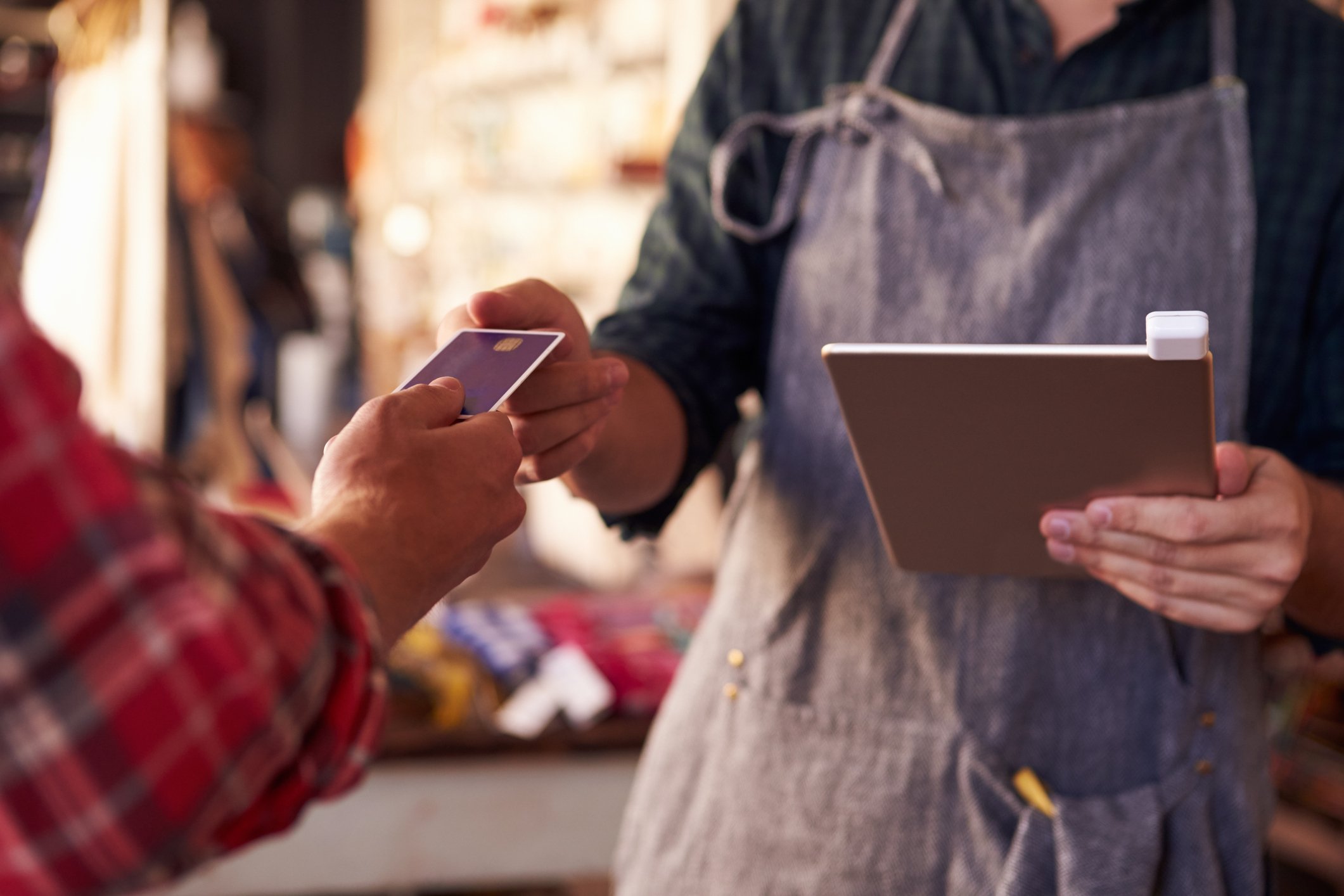 A merchant accepts a credit card while holding a computer tablet.