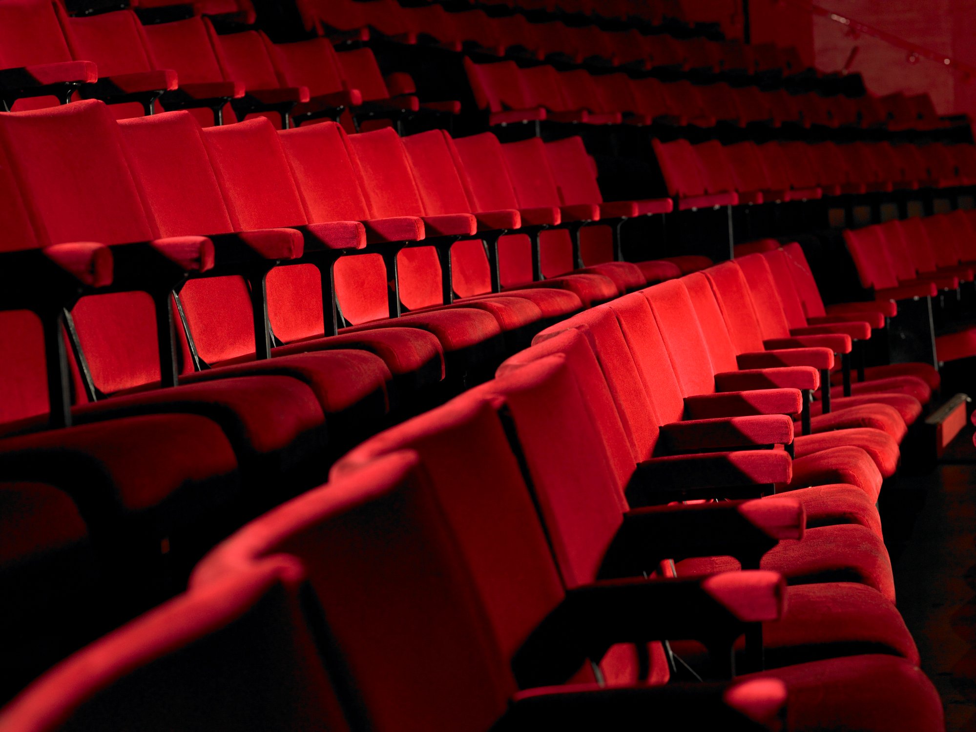 Rows of empty red movie theater chairs.