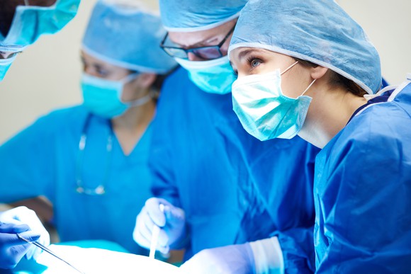 Three surgeons are at work in an operating room.