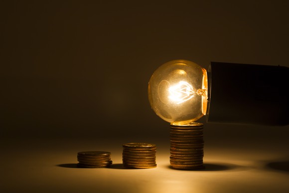 A lit Edison-style bulb on the tallest of three stacks of pennies..