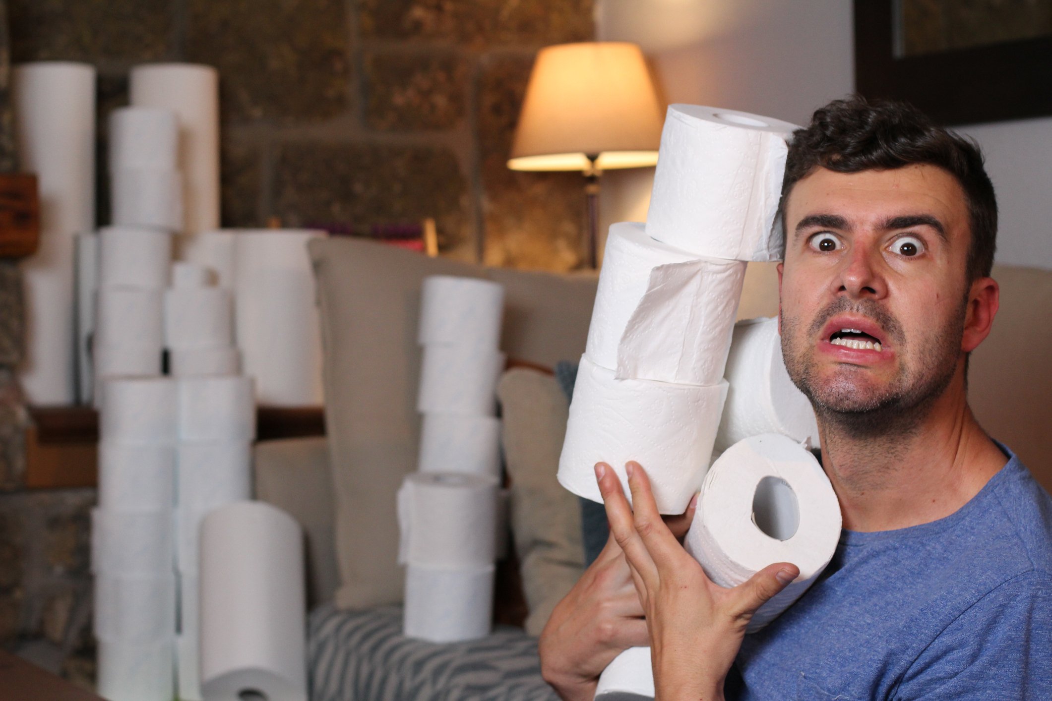 Alarmed man with stacks of toilet paper rolls