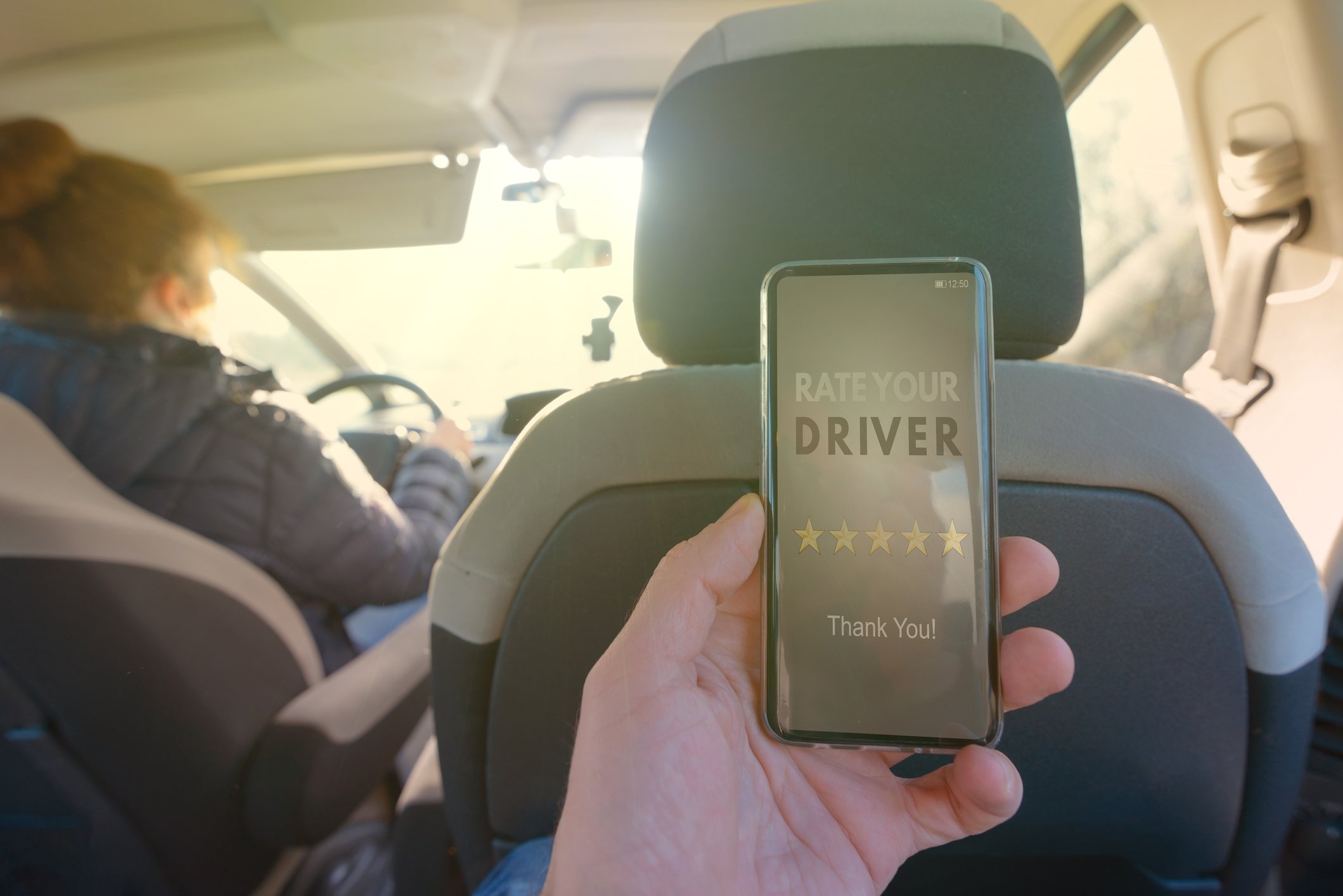 ride-sharing passenger holding phone with driver rating app open