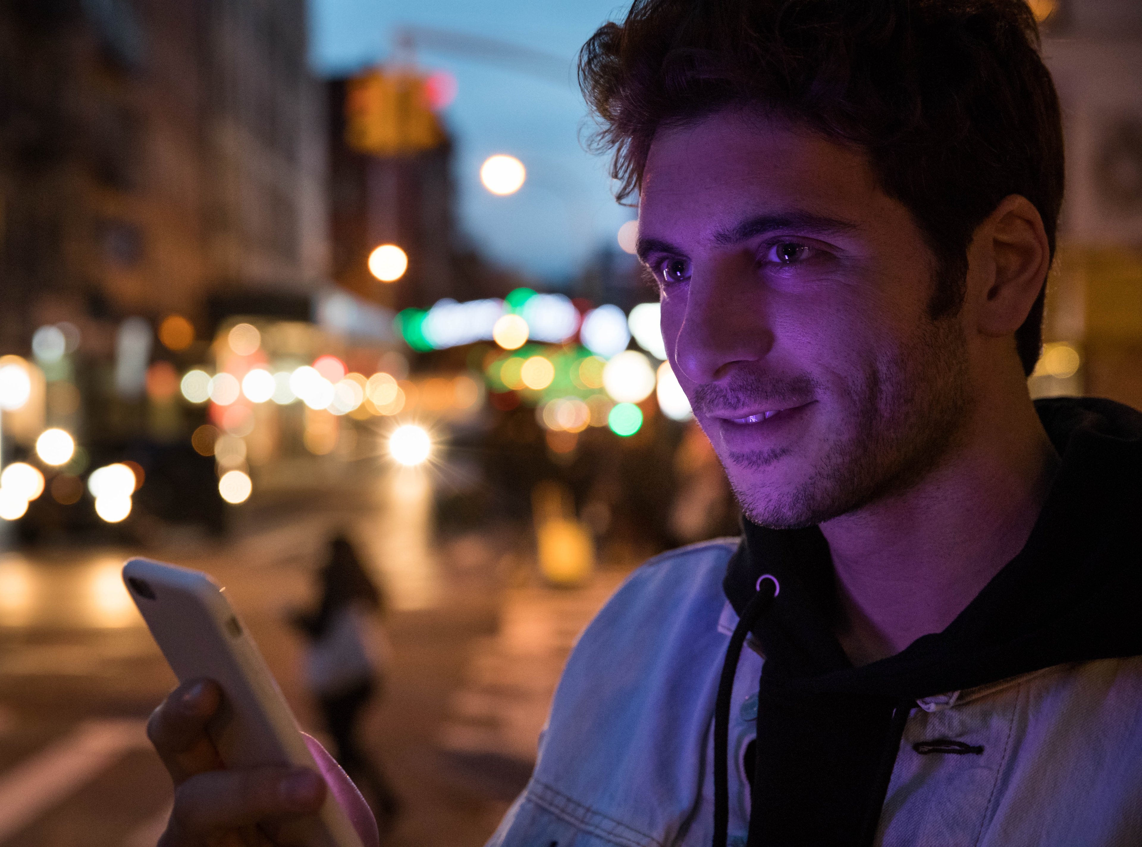 Man waiting for a Lyft on a street corner at night