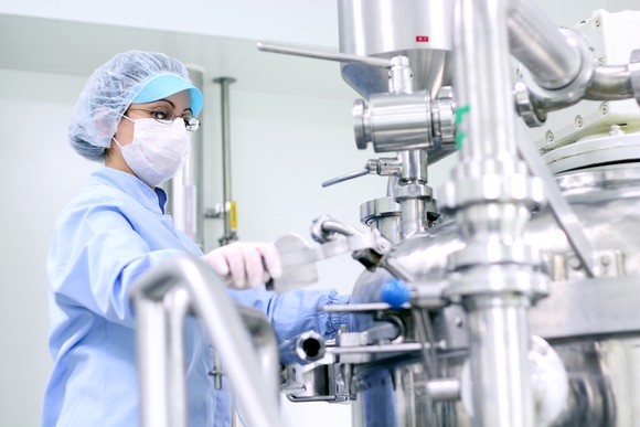 Woman operating pharmaceutical lab equipment.