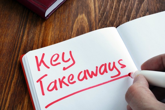 Someone writing the words "Key Takeaways" in red marker in a notebook.