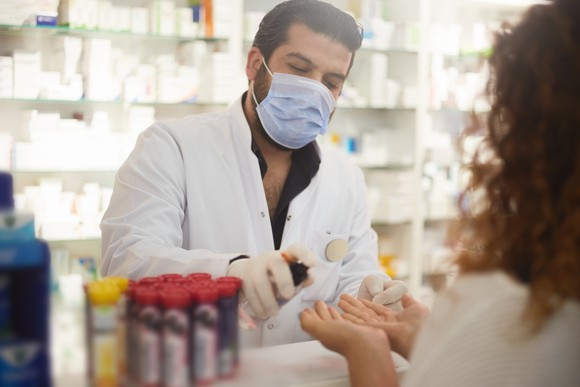 A pharmacist wears a face mask