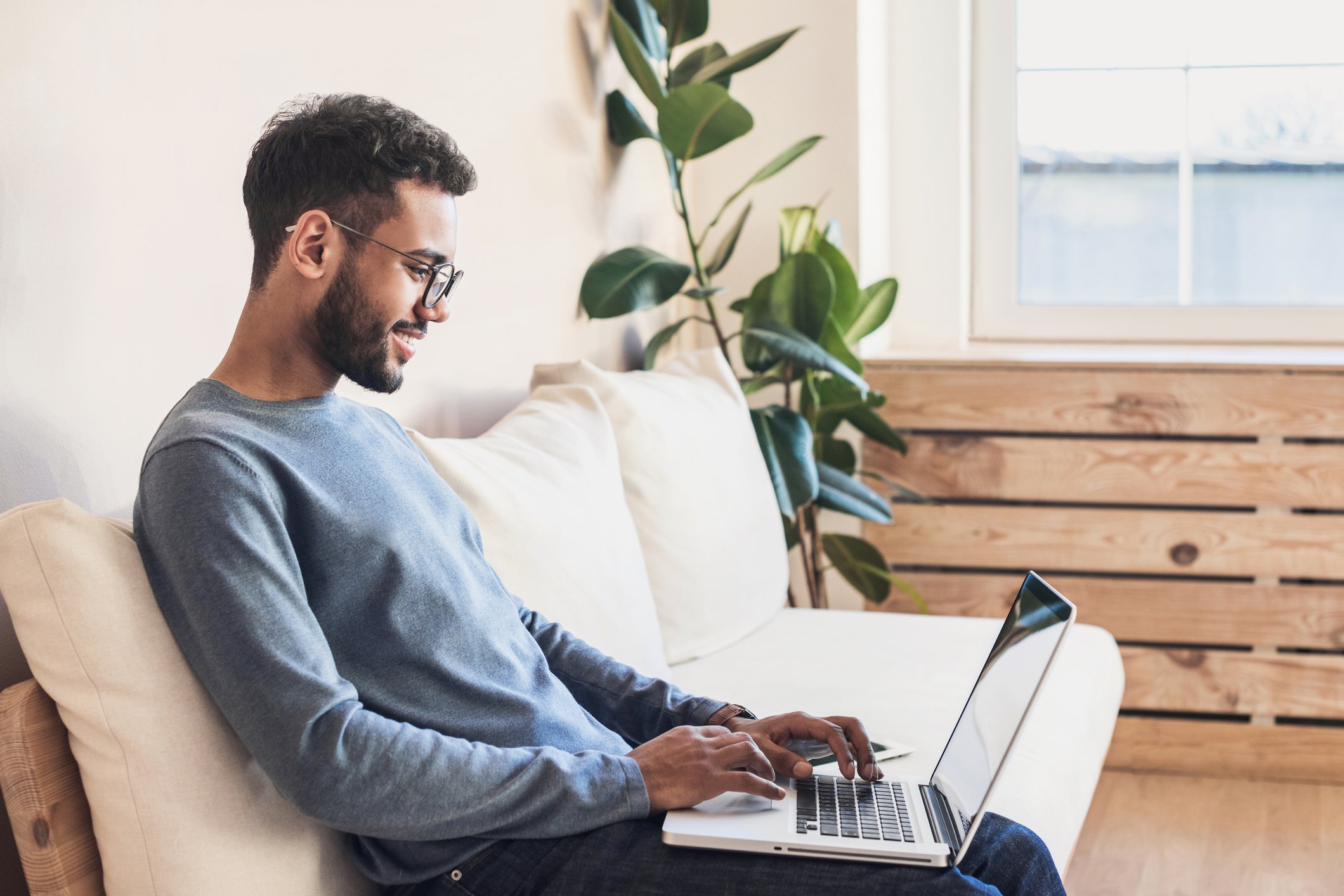 A young man works on his laptop at home.