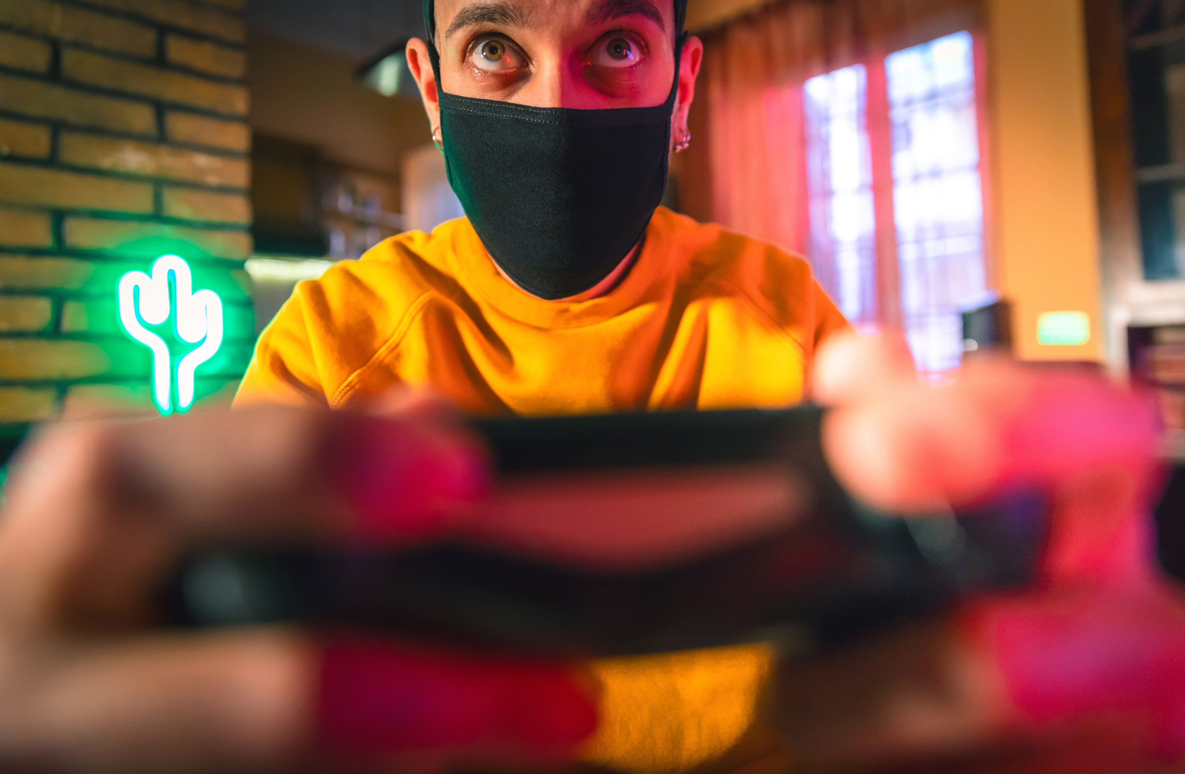 A man playing a video game wearing a mask. 