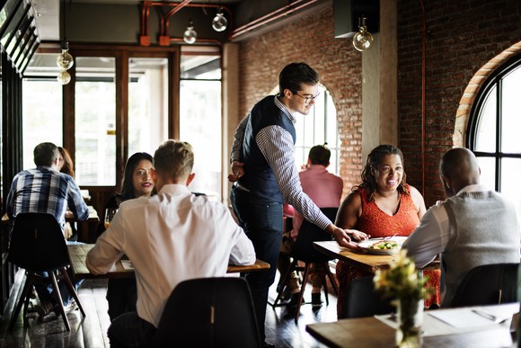 A waiter serving a table of diners.