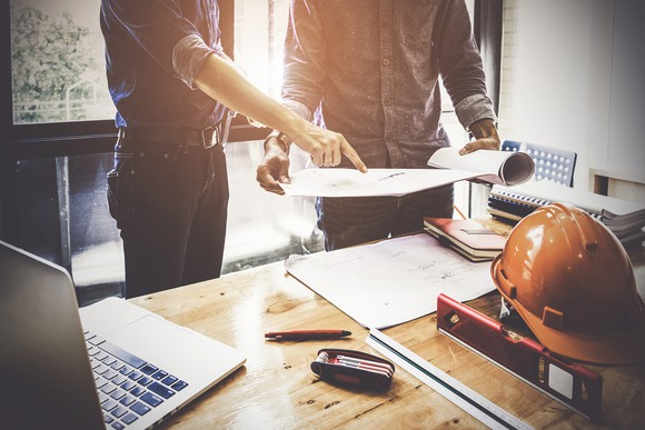 Two men looking at blueprints over a desk
