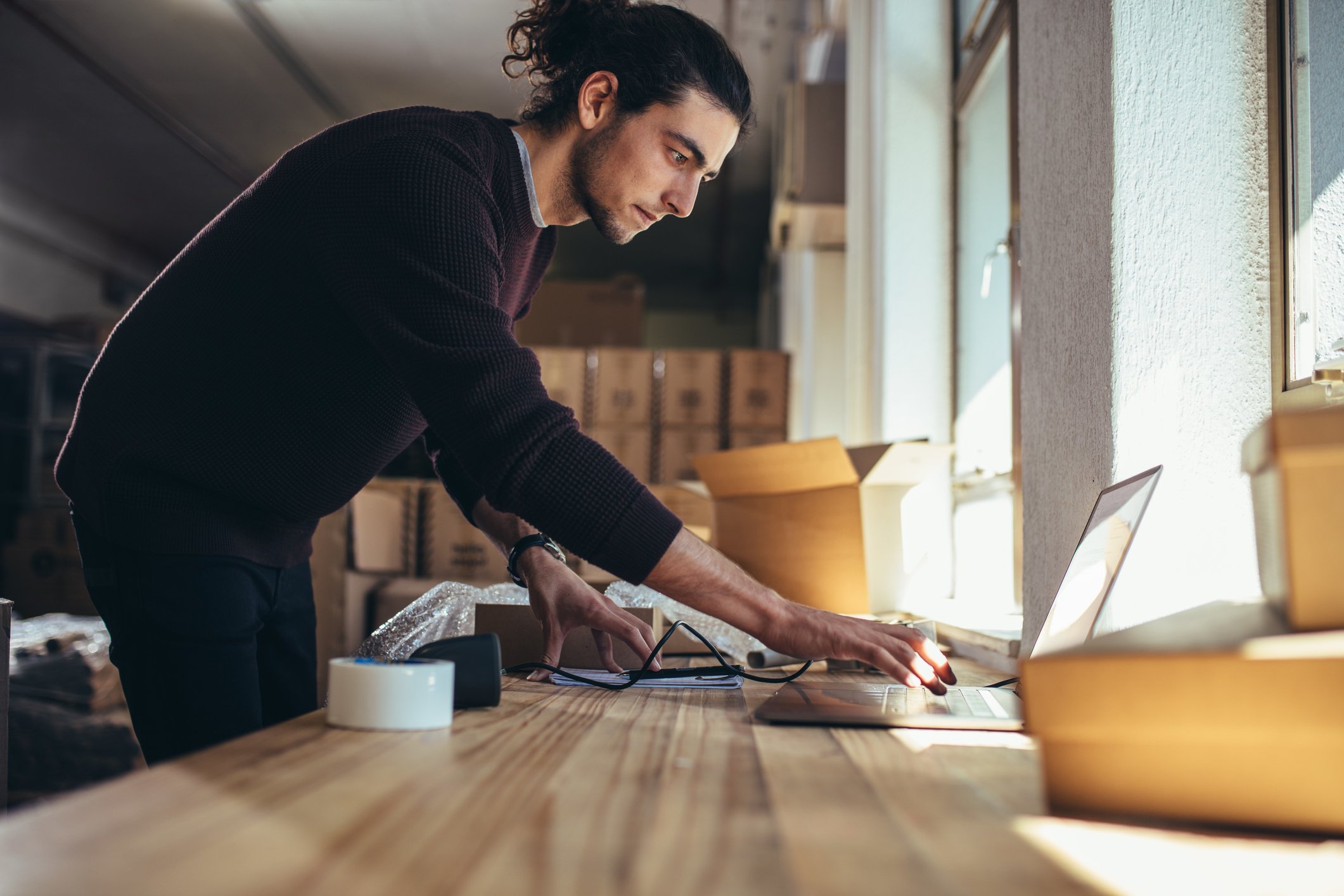 A man working on a laptop next to some boxes
