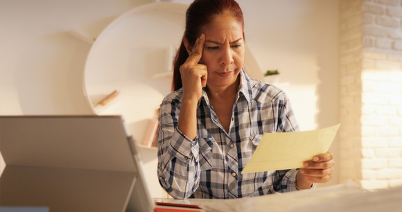 Woman looking at paper, unhappy.