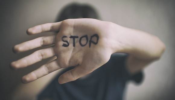 person holding up hand with "stop" written on palm
