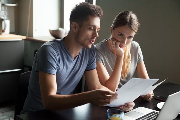 Couple looking at pieces of paper in front of laptop