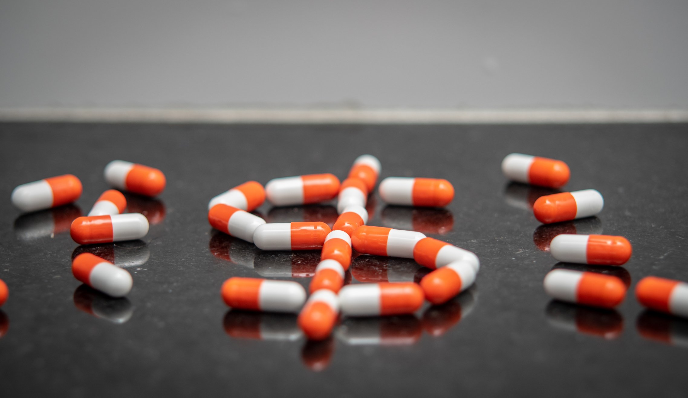 An assort of pills, with the middle one forming a dollar sign.