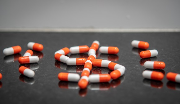 An assort of pills, with the middle one forming a dollar sign.