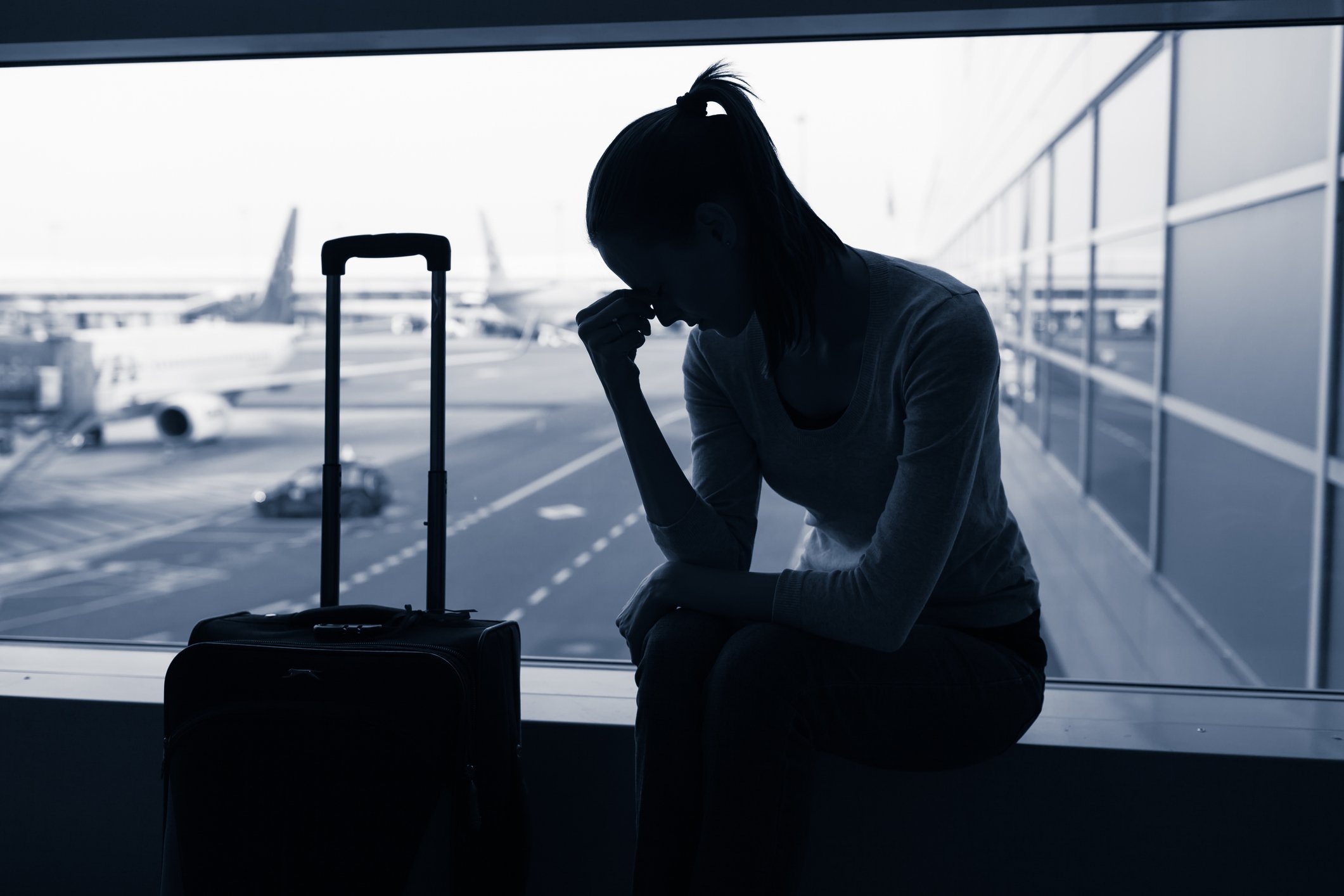 lone traveler sits at airport with head in hands