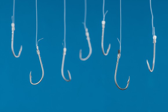 A series of fishing hooks tied to lines against a blue background. 