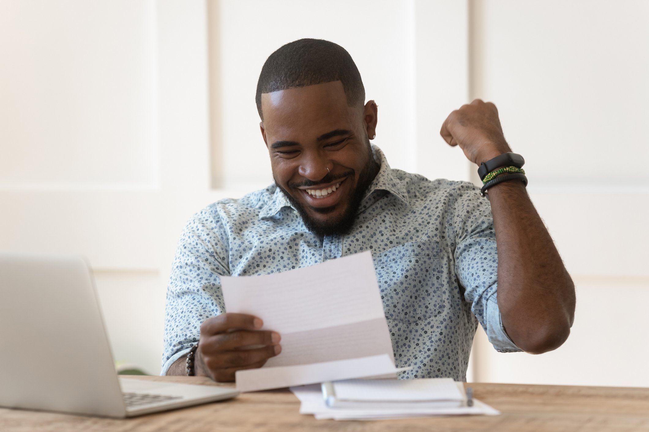 Man reading letter and pumping fist in joy