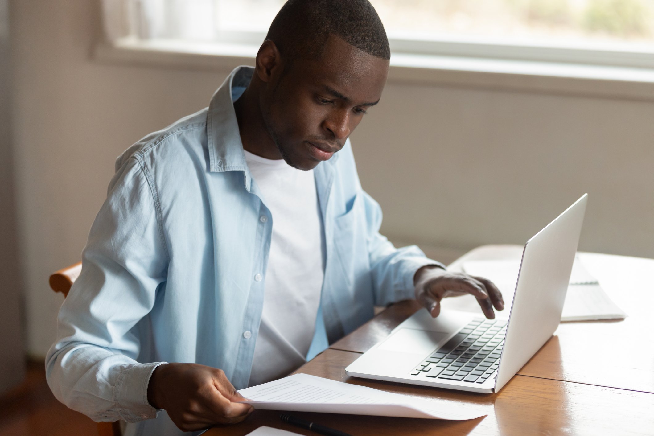 Man reviewing papers in front of laptop
