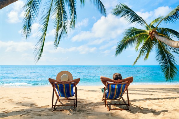 Two people sitting in chairs on the beach. 