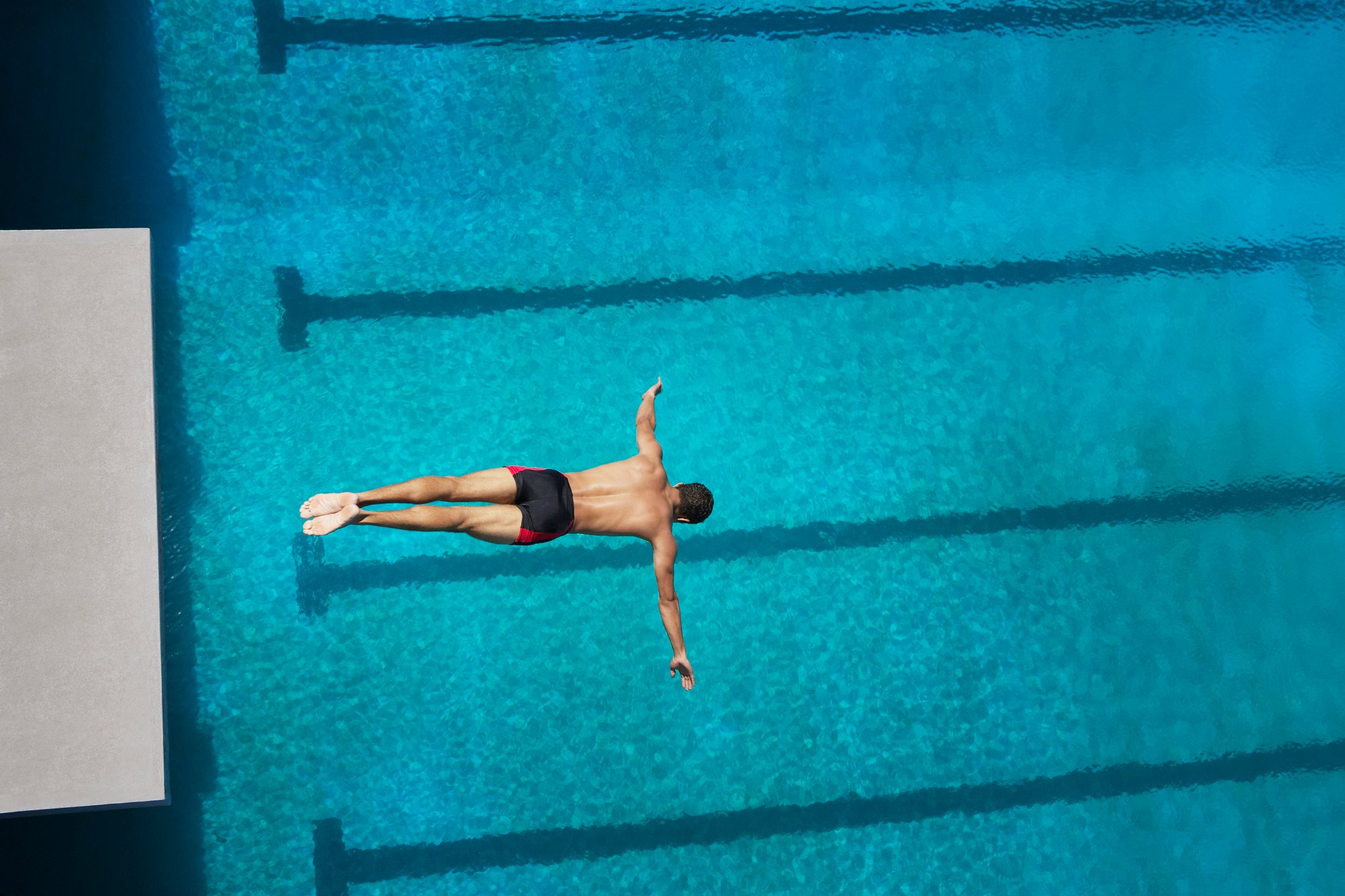 Man diving from a platform into a pool.
