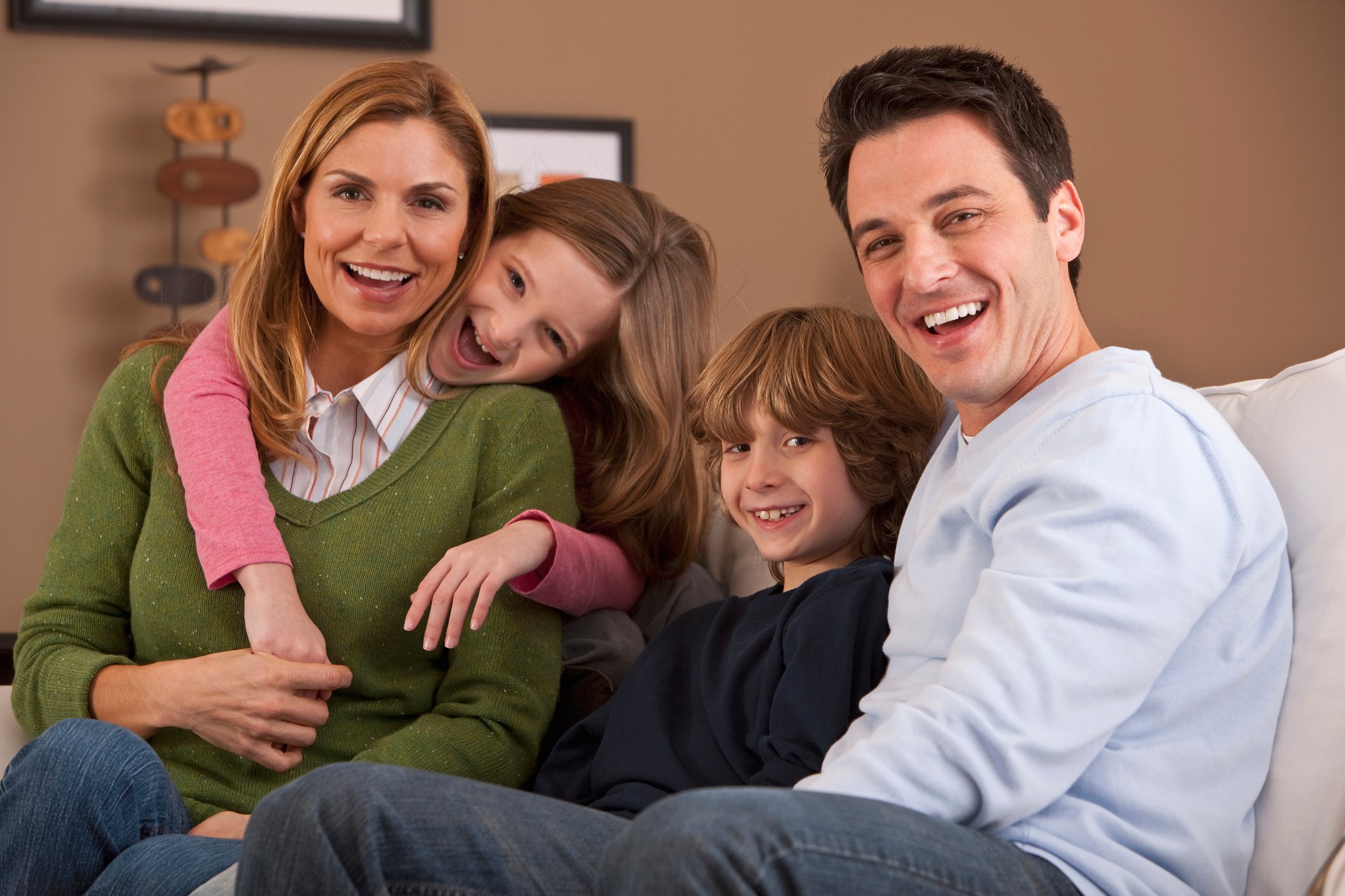 A happy couple seated on the couch with their two children