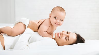 Mother lying down and holding a happy baby