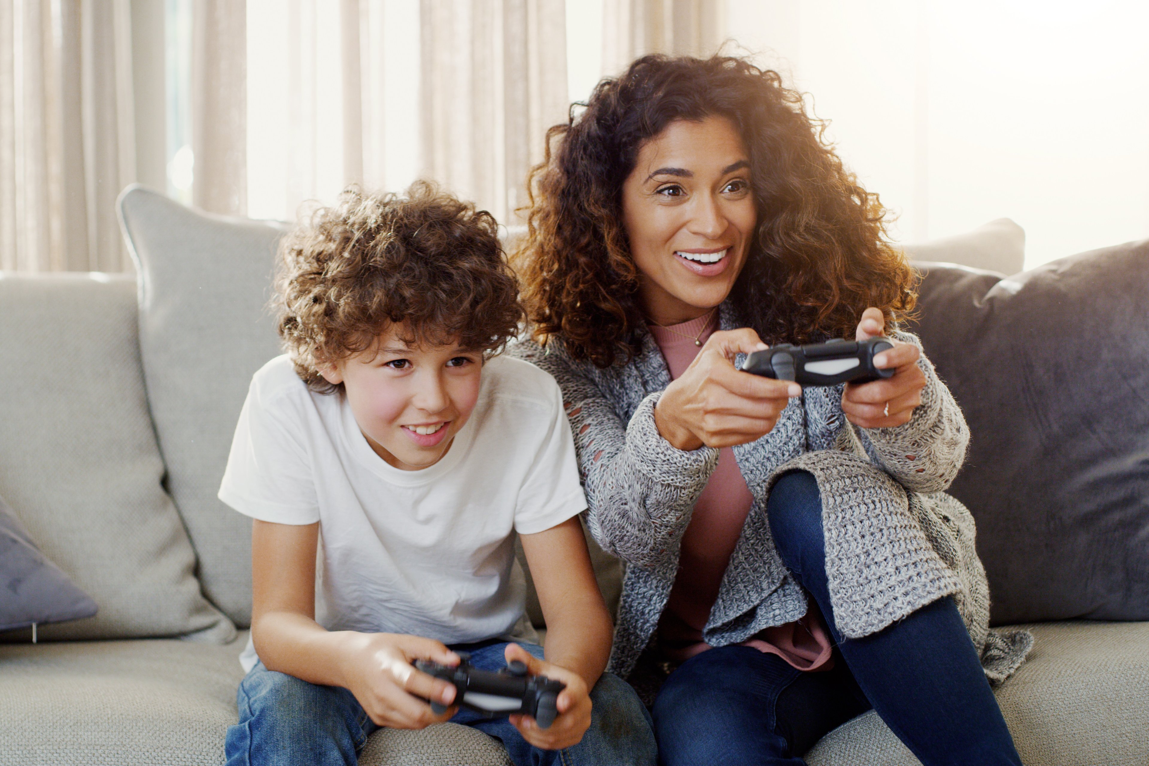 A woman and a boy sitting on a couch playing a console video game