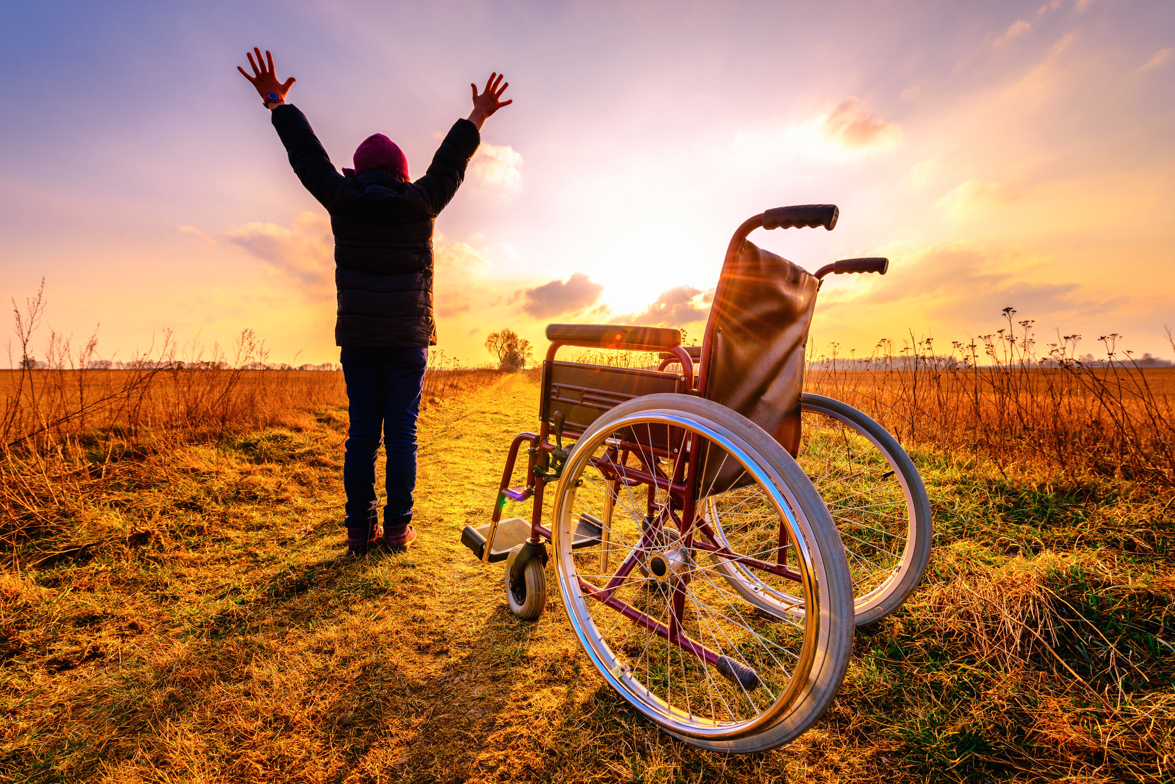 Woman raising her hands high after getting off wheelchair. 
