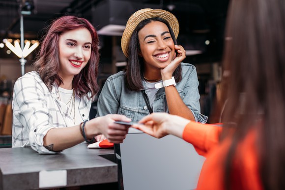 Two young women paying for purchases with a credit card. 