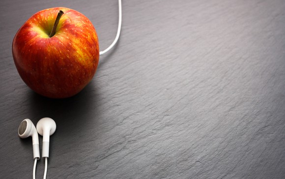 An apple with headphones plugged into it.