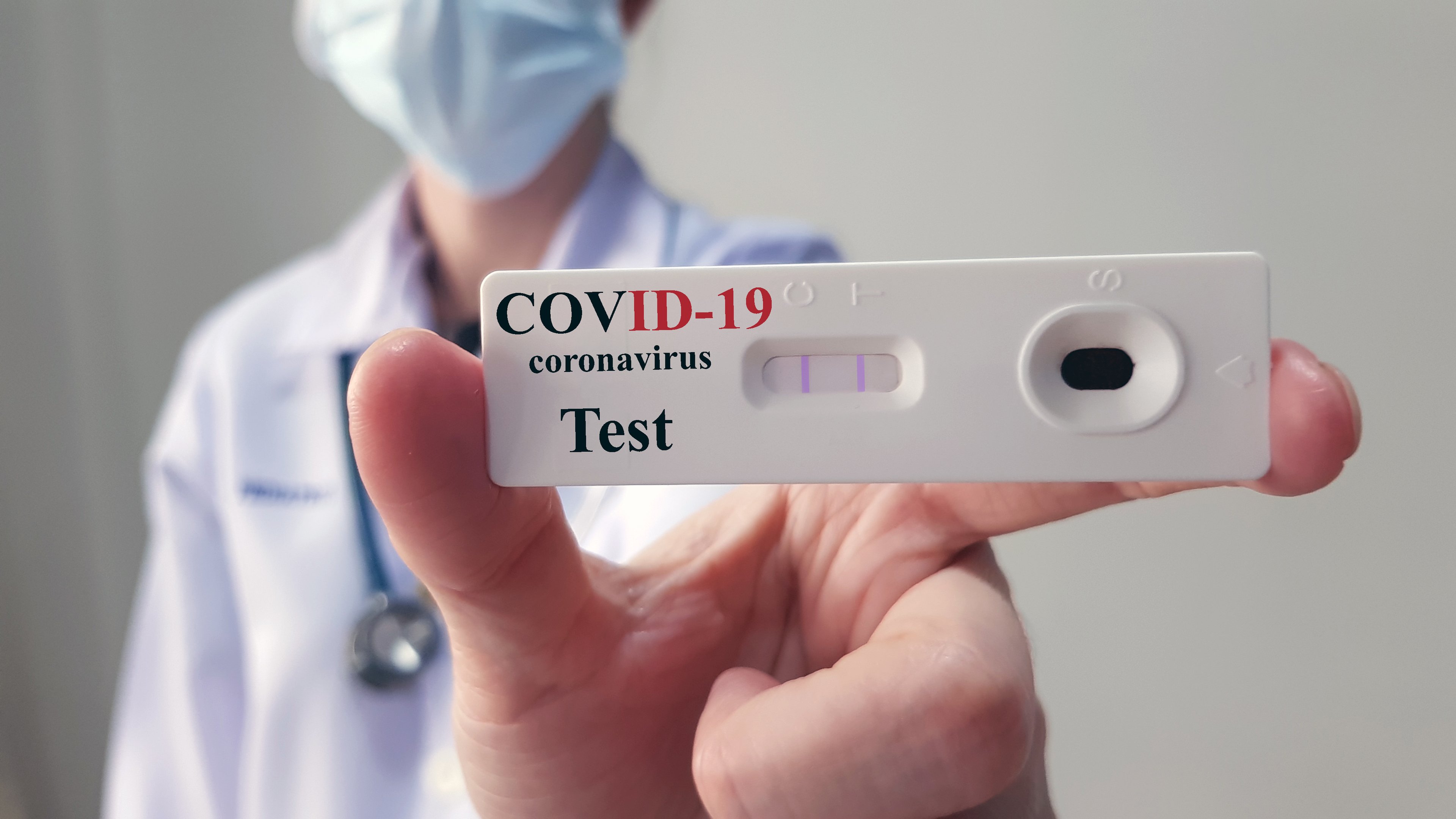 Doctor holding up COVID-19 test kit. 