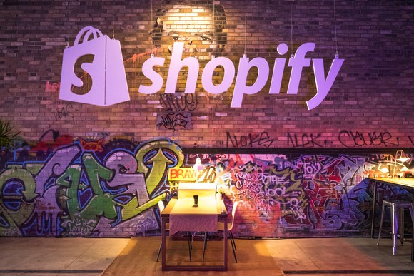 An illuminated Shopify logo above a cafeteria table.