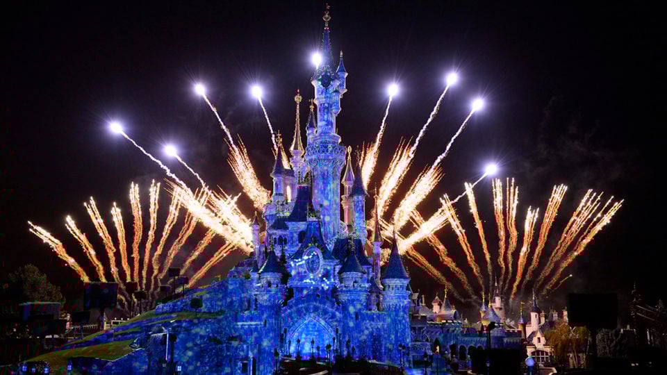 Disney theme park castle with fireworks at night