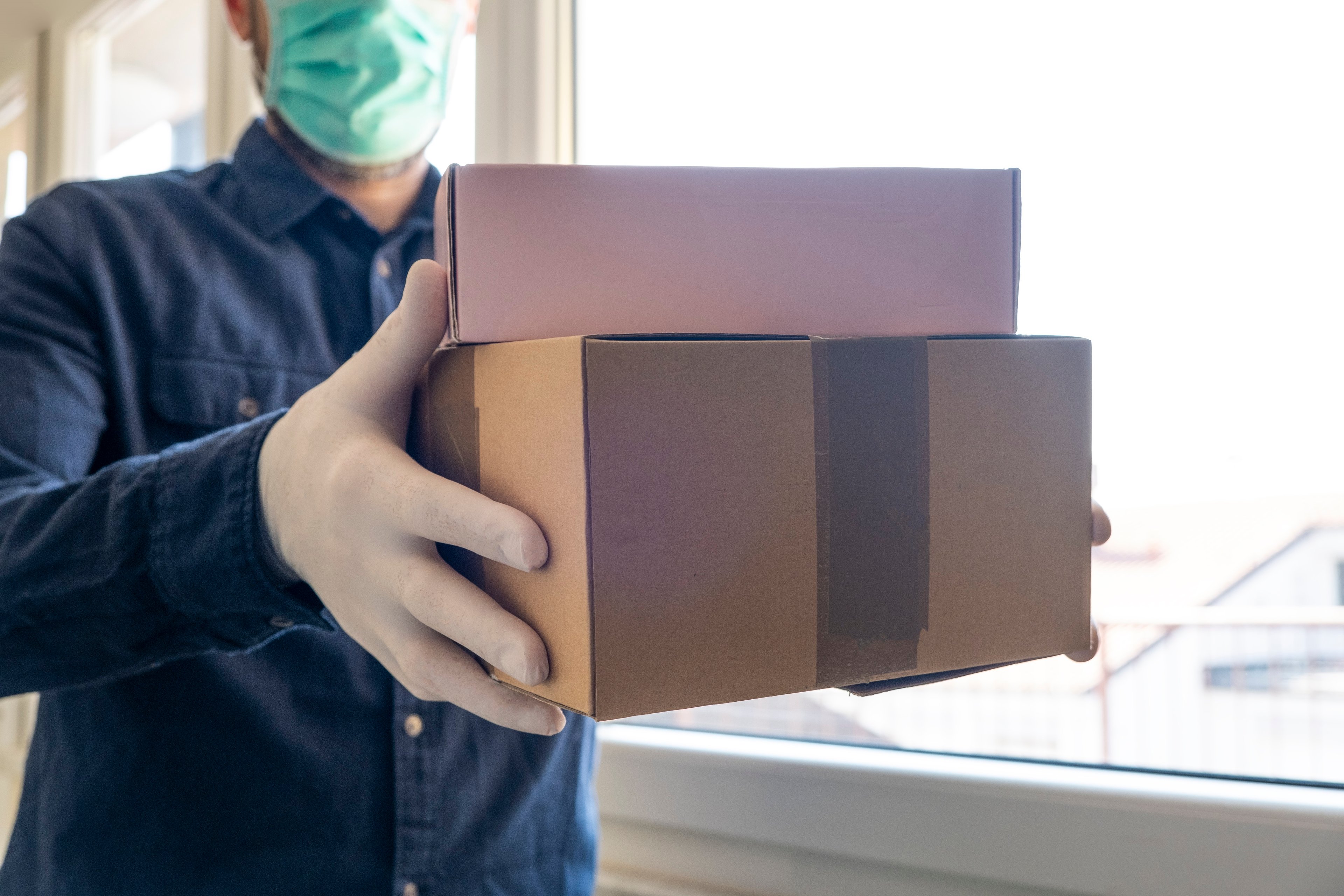 A man wearing a mask dropping off packages. 